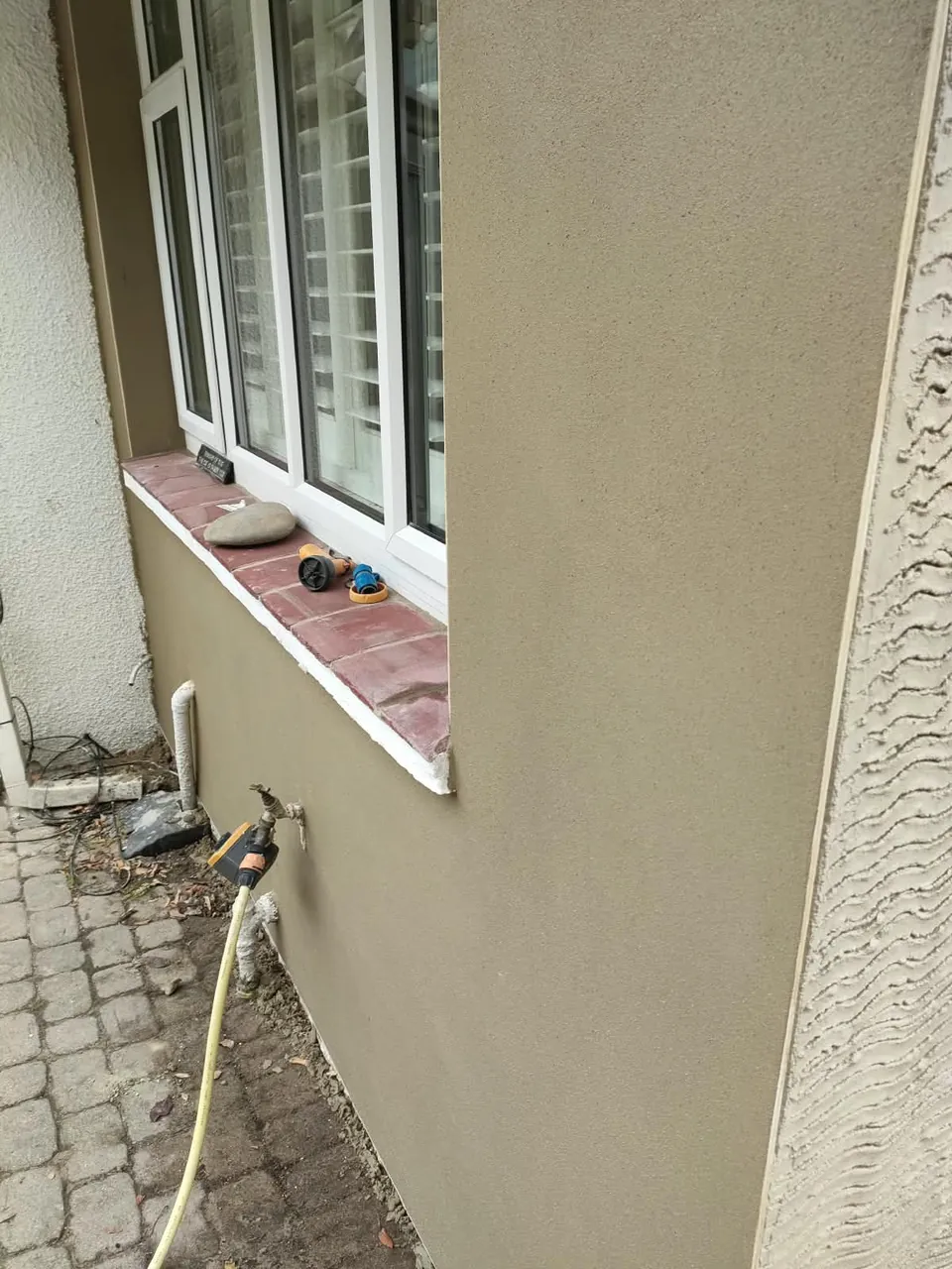 Smooth finished render beside the scratch coat on the same wall, showing the two stages