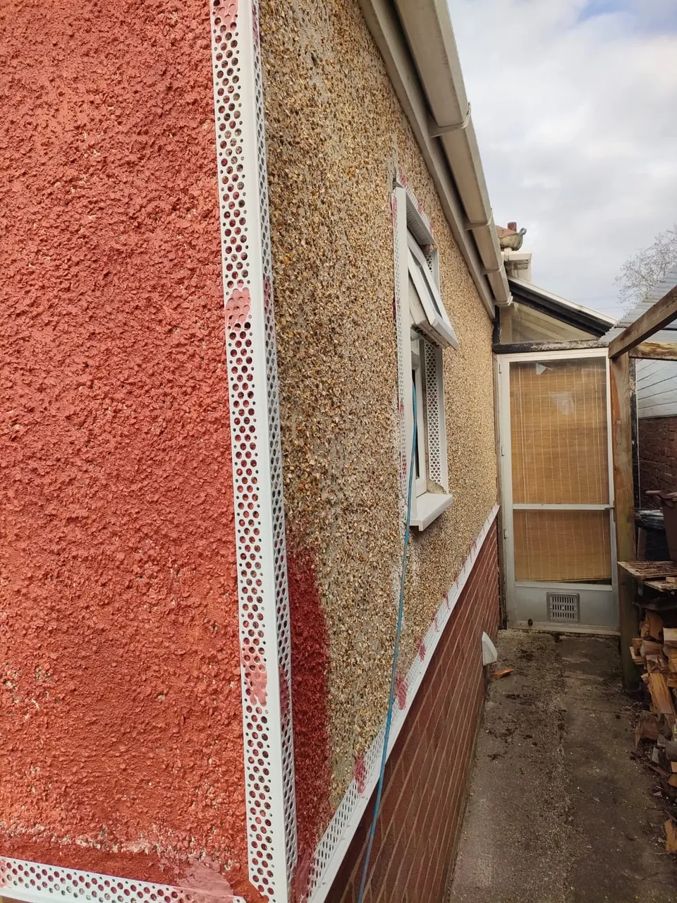 Existing pebbledash side wall of a bungalow with beads fitted ready for render