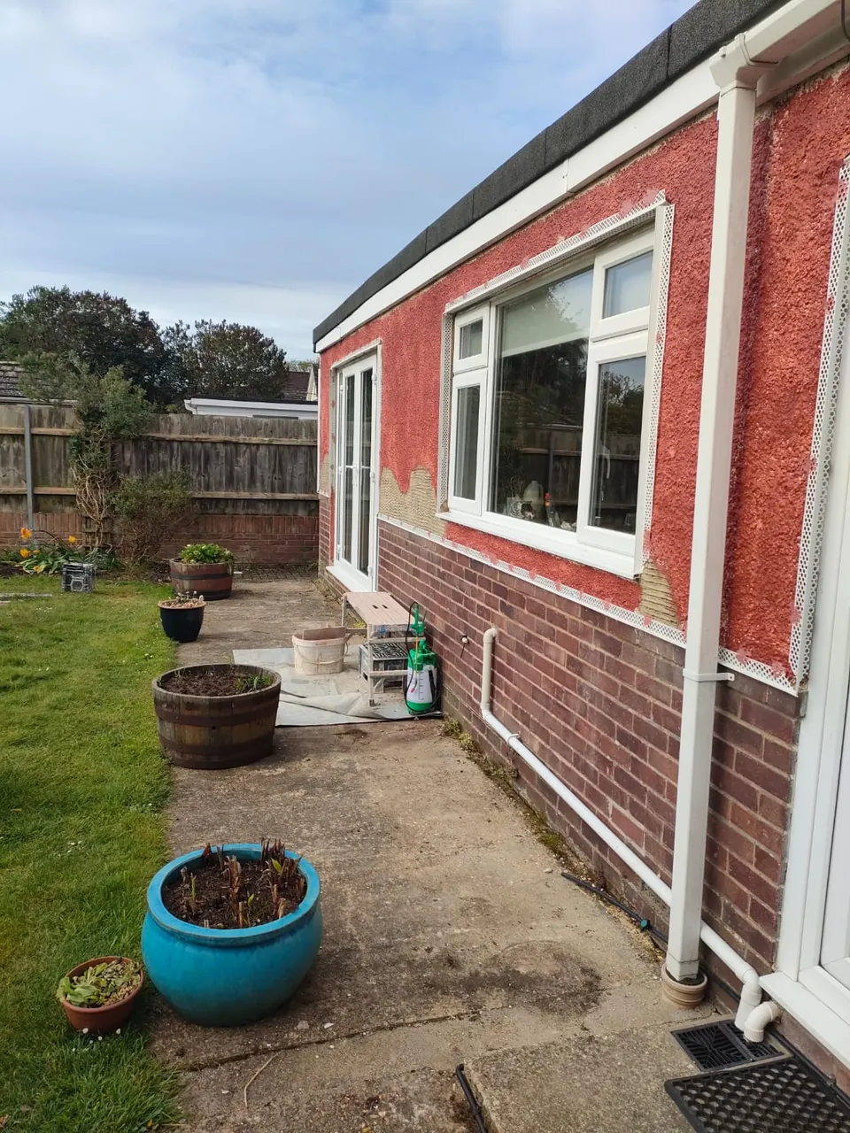 Existing wall coated with a red bonding primer and beads fitted around the window and door