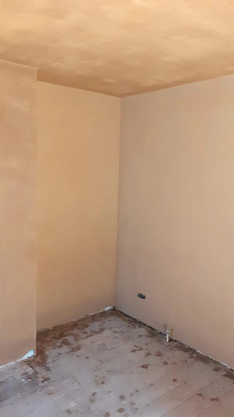 Newly plastered room corner and ceiling over an old floorboard floor