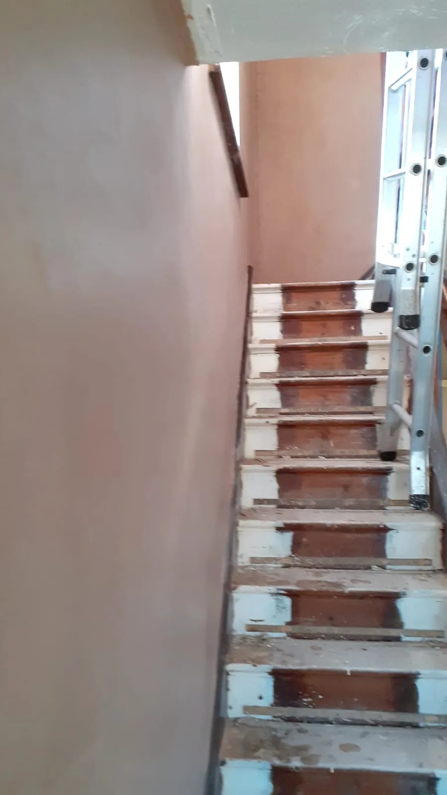 Newly plastered stairwell wall with the stairs stripped back beside it