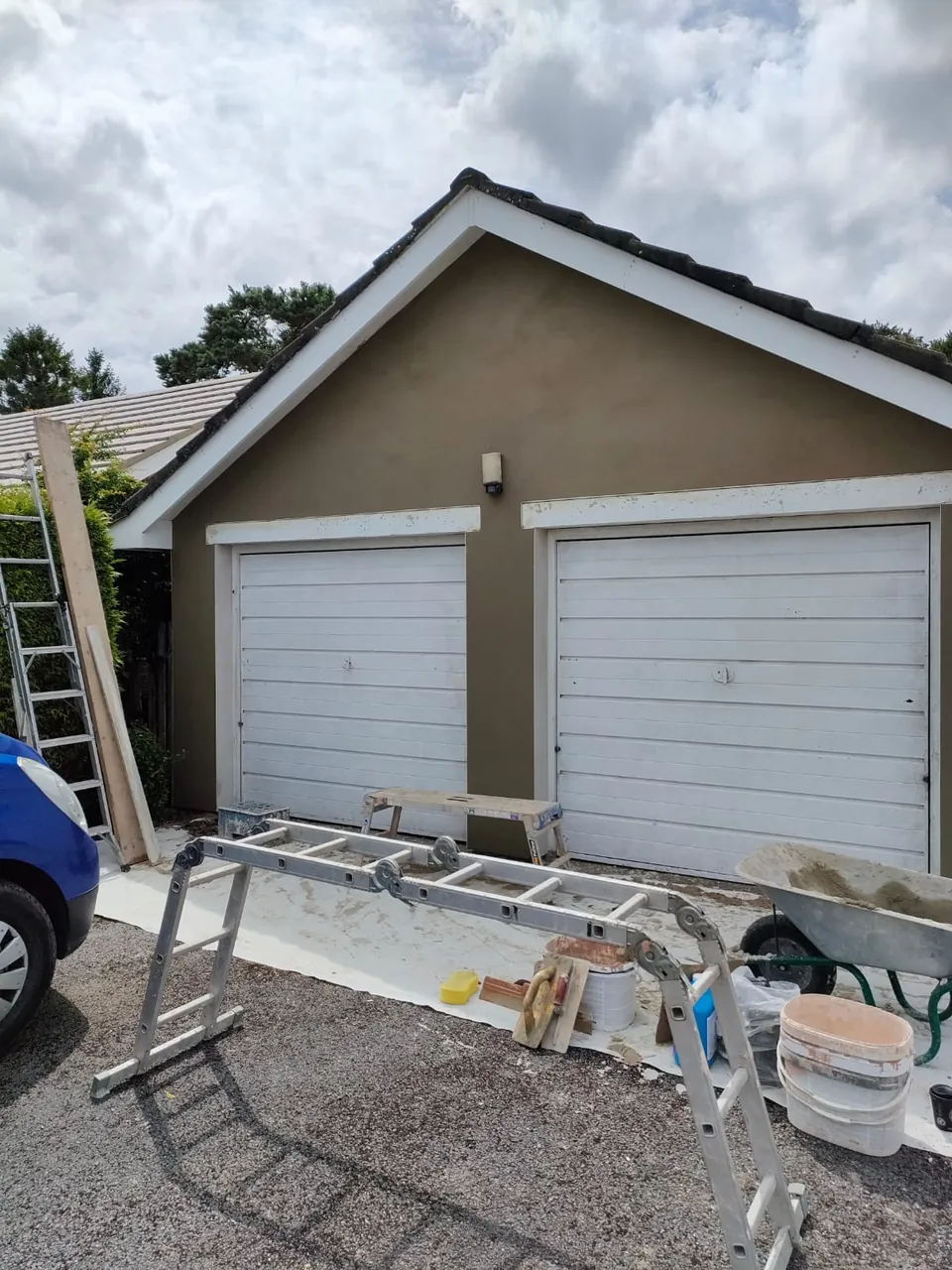 Double garage with smooth finished render and two white up-and-over doors