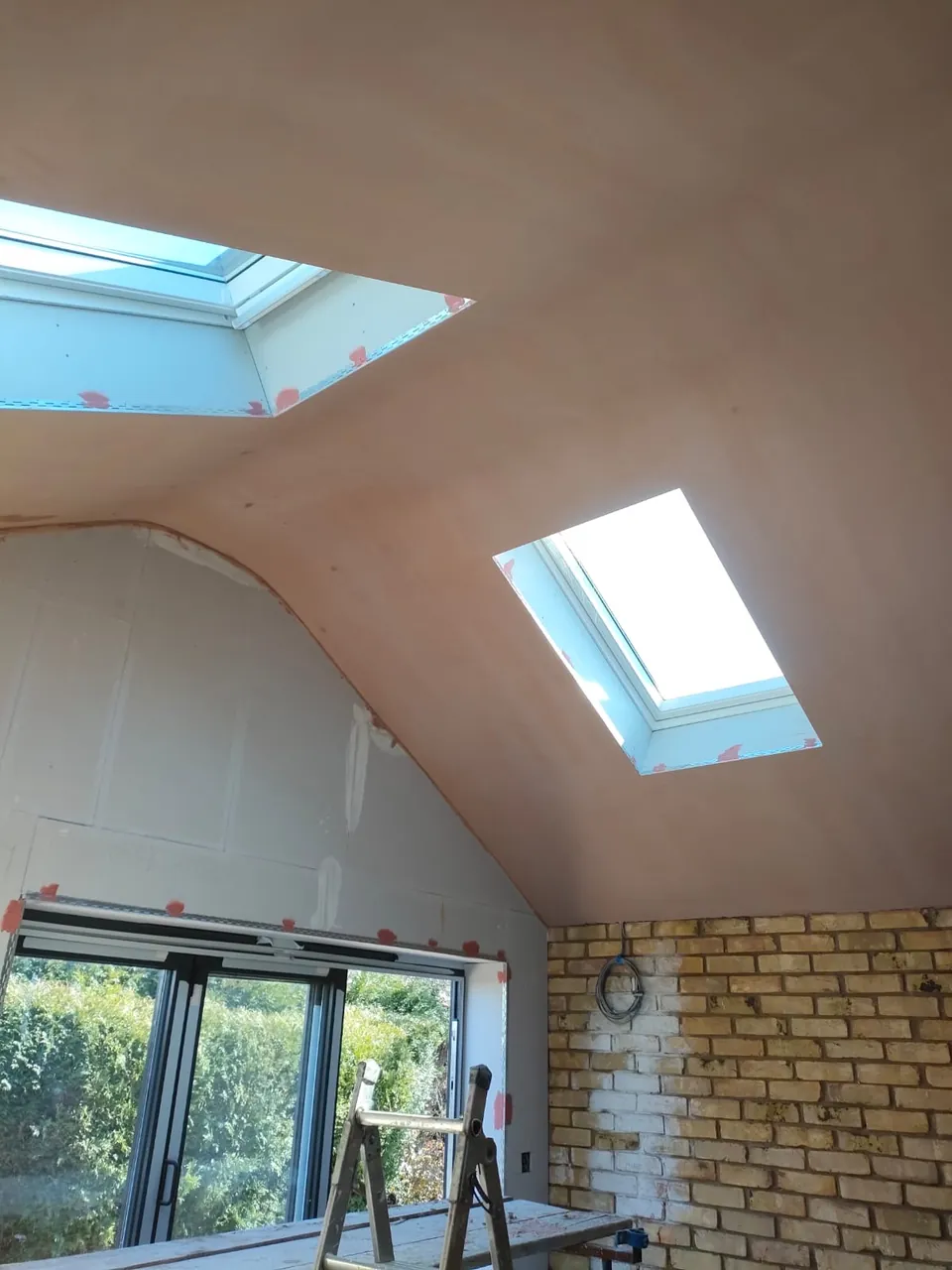 Skimmed vaulted ceiling with two roof windows, a boarded gable wall and bifold doors